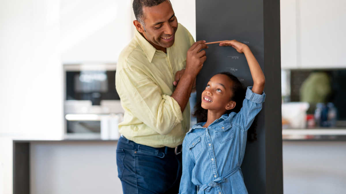 a father measuring the height of a little girl